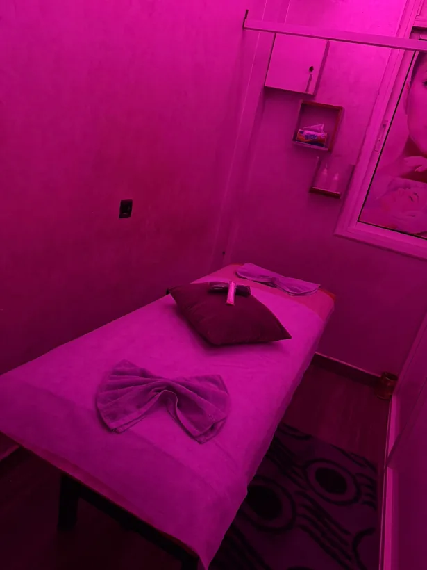Table de massage sous une lumière rose chez Malouka Spa à Marrakech
